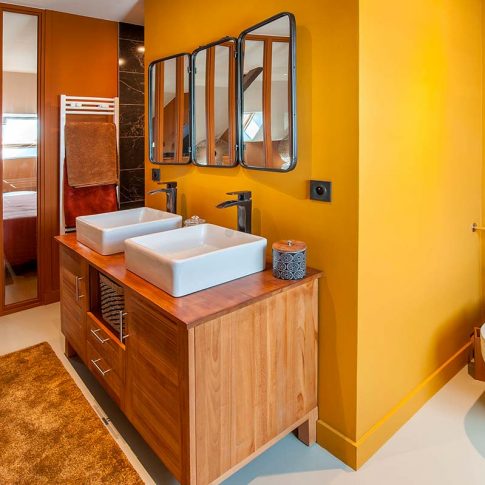 salle de bain couleur ocre et meuble double vasque en bois dans chambre parentale sous comble